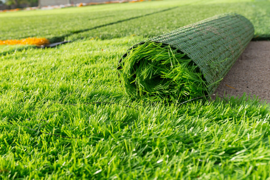 roll of artificial turf being installed