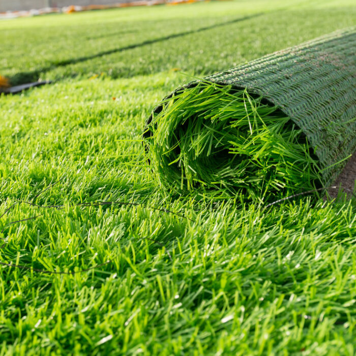 roll of artificial turf being installed