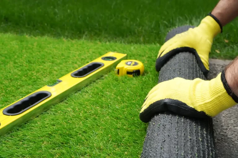 landscaper wearing gloves and rolling out some artificial grass